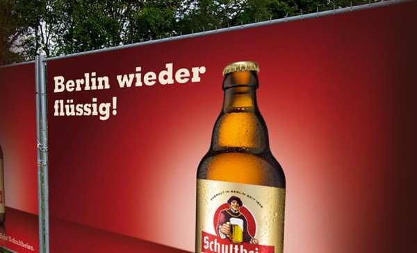 Ein großes Werbebanner zeigt eine Getränkeflasche vor einem roten Hintergrund. Der Slogan lautet: Berlin wieder flüssig.