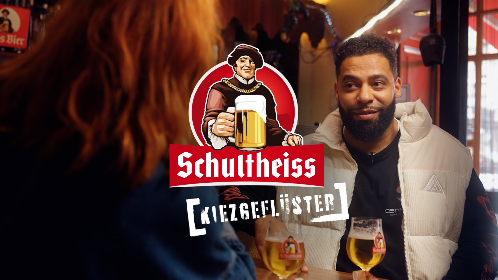 Interviewsituationen zweier Personen in einer Kneipe, im Vordergrund ein grafisches Logo mit dem Text Schultheiss Kiezgeflüster. 