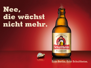 Eine Bierflasche steht neben einem Kronkorken auf rotem Hintergrund. Der Text lautet in großer Schrift.