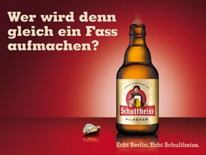 Eine Flasche Bier steht neben einem Kronkorken auf rotem Hintergrund.