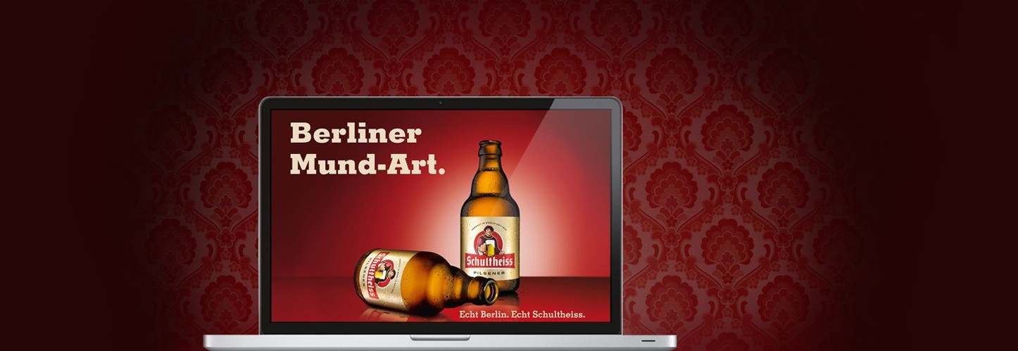 Ein Laptopbildschirm zeigt eine Bierflasche und ein Glas auf rotem Hintergrund.