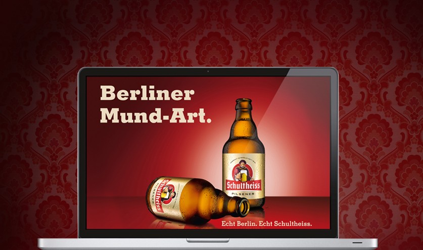 Ein Laptopbildschirm zeigt eine Bierflasche und ein Glas auf rotem Hintergrund.